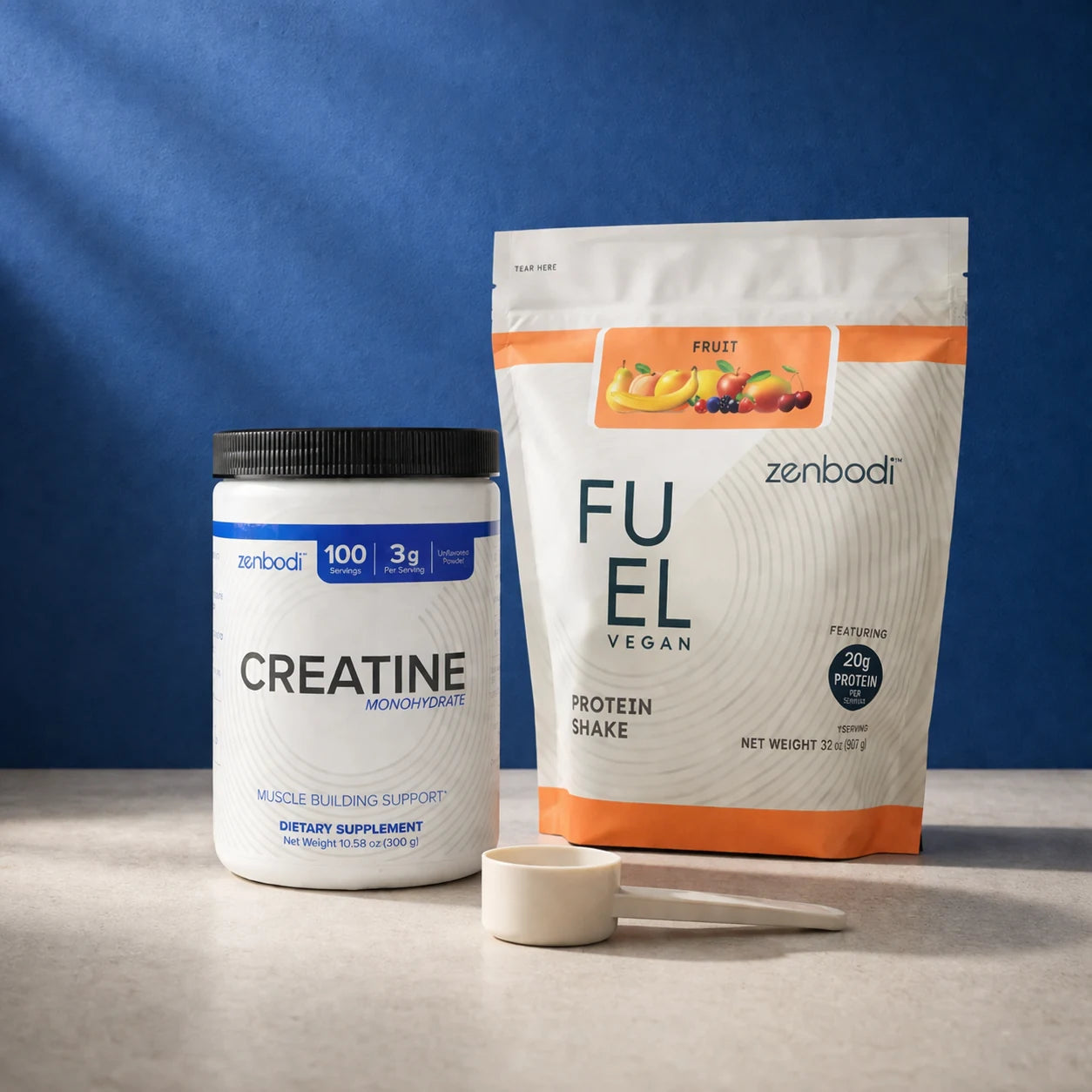 Zenbodi Creatine tub and FUEL Vegan Protein bag with ceramic scoop on a cobalt blue backdrop