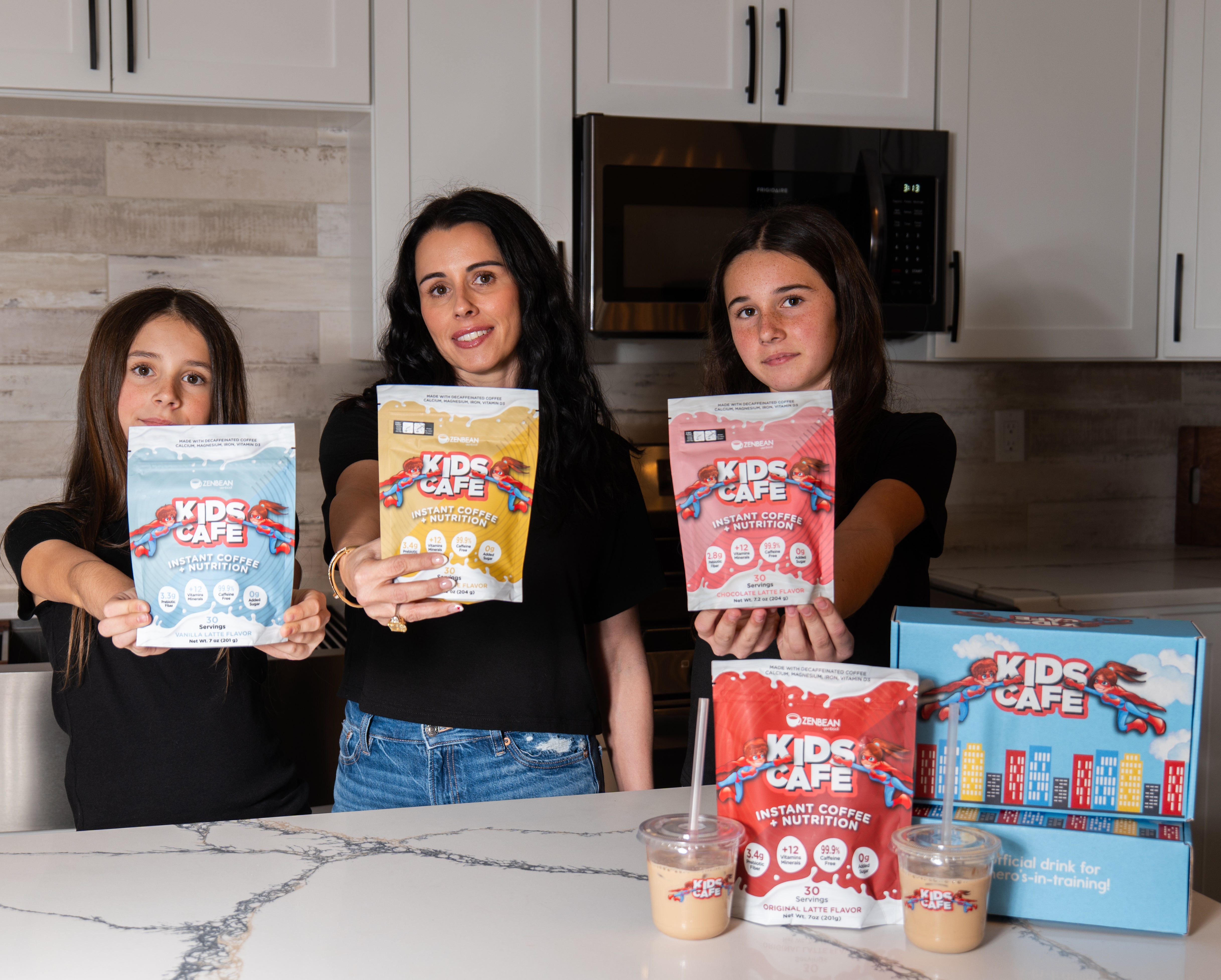Hollie Mancini, founder of Kids Cafe, with her two daughters in their kitchen holding Kids Cafe pouches